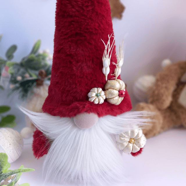 Tomte lutin de Noël au bonnet rouge et citrouilles dorées
